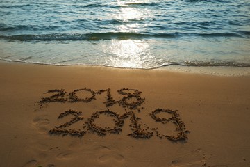 Happy new year concept, 2018 is going to pass, 2019 is coming write on sand beach in sunset.