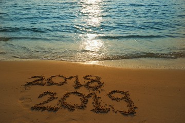 Happy new year concept, 2018 is going to pass, 2019 is coming write on sand beach in sunset.