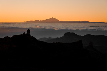 GRAN CANARIA, SPAIN - NOVEMBER 6, 2018: Morning landscape of Roque Nublo mountain under the orange misty sky and Tenerife island