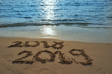 Happy new year concept, the year 2018 is going to pass 2019 is coming write on sand beach in sunset.