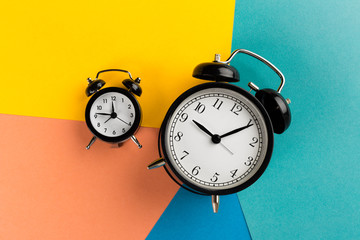 Vintage black alarm clock on a color block background