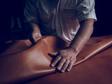 Midsection of craftsman laying leather on table