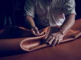 Midsection of craftsman laying leather on table