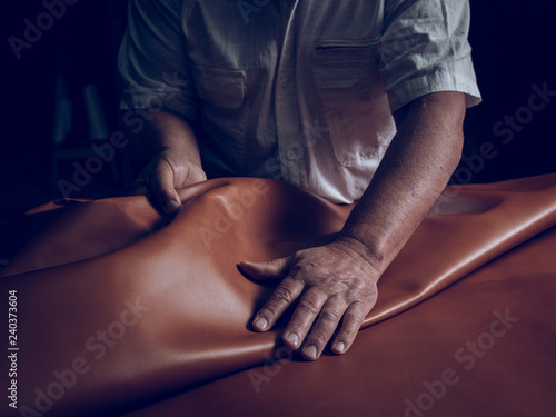 Midsection of craftsman laying leather on table