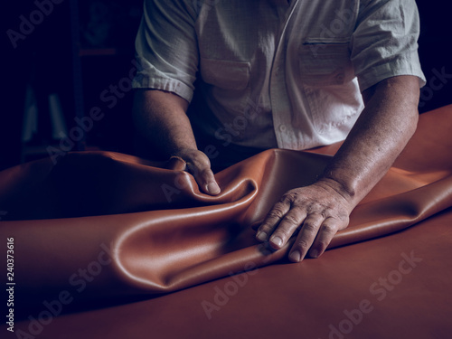 Midsection of craftsman laying leather on table
