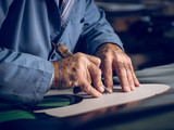 Close up of shoemaker cutting shoe template on leather