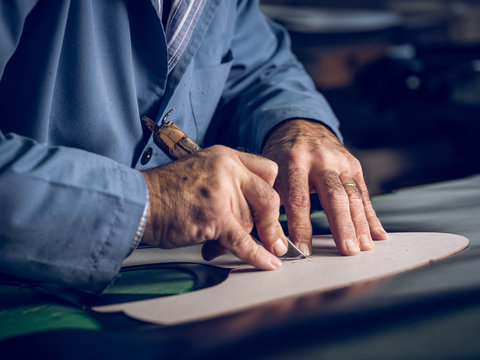 Close up of shoemaker cutting shoe template on leather