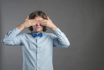 Man covering his eyes with hands on gray background. Shy male closing eyes by hands can't see hiding, wall background. See no evil concept. Negative human emotion, facial expression, feeling reaction