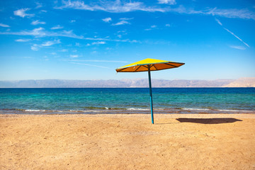 Beach on the shore of the Red Sea. Umbrella, water and beach. Resort in the Aqaba, Jordan near Israel Ejlat.
