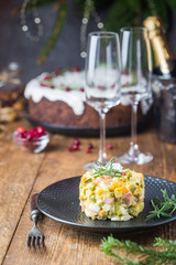 Traditional Russian salad with cooked vegetables with mayonnaise in a plate. Wooden background.