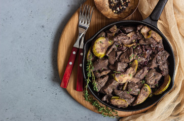 Fried chicken liver with apples, onions and thyme in a frying pan. 