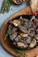 Fried chicken liver with apples, onions and thyme in a frying pan. 