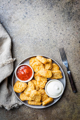 Crispy fried chicken nuggets with tomato sauce. Top view. Stone background