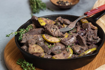 Fried chicken liver with apples, onions and thyme in a frying pan. 