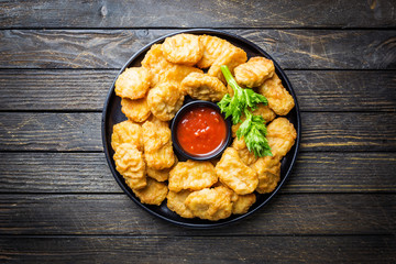 Crispy fried chicken nuggets with tomato sauce. Top view. black background