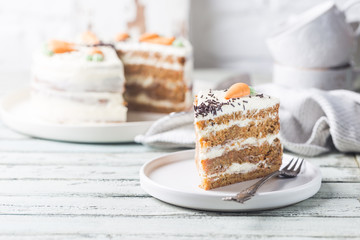 Healthy homemade carrot cake with cream cheese frosting on white wooden table
