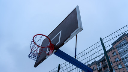 Basketball shabby backboard with a red basketball hoop in cloudy weather