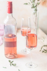 Two glasses and bottle of rose wine on light background.