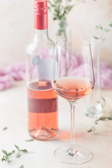 Glass and bottle of rose wine on light background.