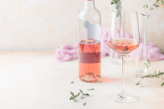 Glass and bottle of rose wine on light background.