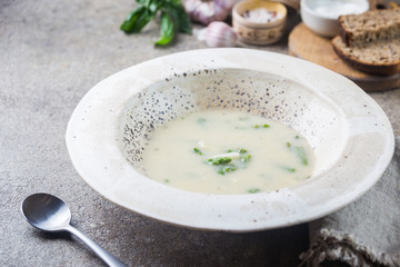 Fresh asparagus cream soup in a bowl over gray stone table