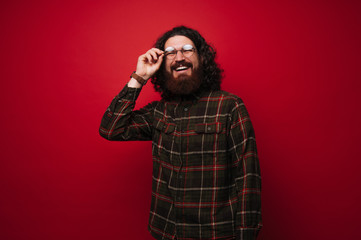 Photo of handsome bearded man in glasses and shirt over red background