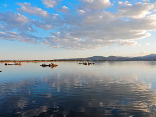 Fototapeta na wymiar Expanse of sea water with soft ripples reflecting the clouds in the colorful sunset sky