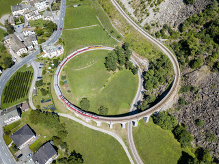 A train is going through the famous circular viaduct in Swiss Alps mountain, Brusio, Canton...
