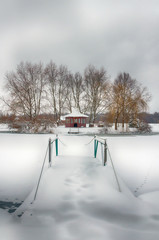 The winter landscape with forest, lake in the bad weather condition