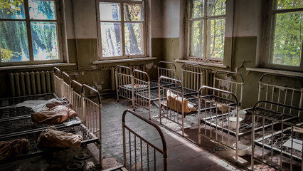 empty children's beds in an abandoned kindergarten house with peeling walls in Chernobyl