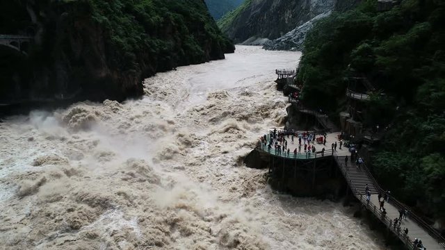 Drone shot of tourists admiring rapid currents of famous Tiger Leaping Gorge in Yunnan province, China