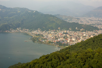Fototapeta premium view from the mountains to the city by the lake on the background of green mountains and their silhouettes. city in a mountain valley
