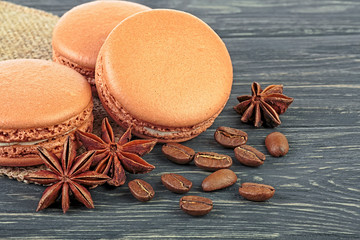Brown macaroons with coffee beans and anise stars on wooden table