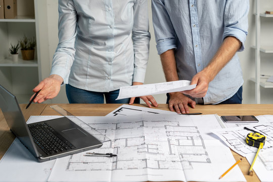 Collaboration brainstorming partners partnership concept. Cropped photo of small group two colleagues specialist designer person in formal wear standin loft interior hold pencil in hand read graphic