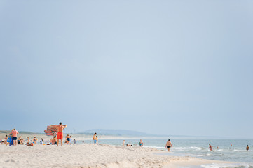 Fototapeta na wymiar Tourists relax in the sea and on the sandy beach