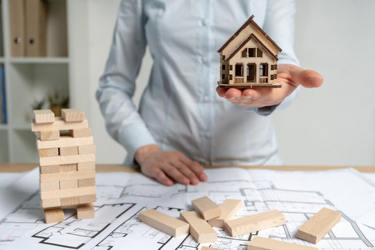 Consumer and consumerism concept. Businesswoman in her formal wear standing indoor light workplace office. She holding little house object in hand making opportunity for rental flat or apartment