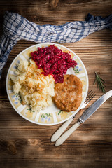 Pork cutlet with minced meat served with boiled potatoes and beetroot.
