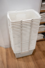 Stack of white baskets on wooden floor in clothing retail shop.