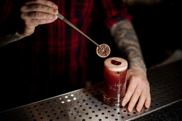 Bartender decorating a Sippy Cup cocktail with a dried orange