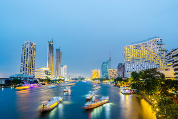 Cityscape of boat light trails on Chao Phraya River night scene in Bangkok, Thailand.
