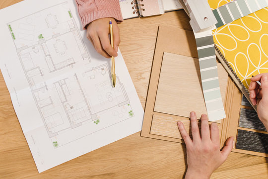 View from above of two women interior designers discussing about blueprints