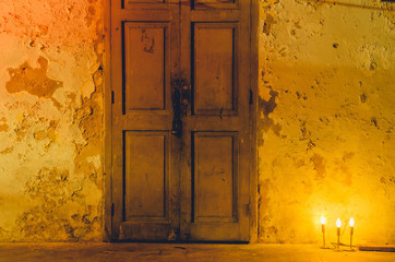 Naklejka premium Orange light from black lamp was front on old white dirty wall that have black stain at night and copy space , concept scary