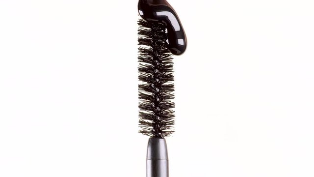 drops of black mascara fall on the brush on a white background