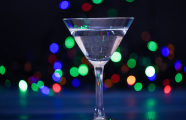 Alcohol cocktail for winter party. Cocktail ideas concept. Easy recipes for winter alcoholic cocktail drinks. What to drink on christmas party. Cocktail glass on defocused garland colorful lights