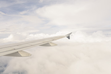 View of the wing of an airplane with blue sky and white clouds background
