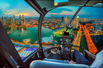 Helicopter cockpit interior on twilight panorama of Singapore marina bay with illuminated...