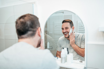 Happy young man shaving.