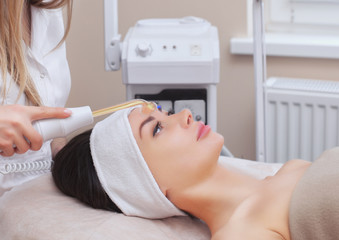 Obraz na płótnie Canvas The doctor-cosmetologist makes the Microcurrent therapy procedure of a beautiful, young woman in a beauty salon.Cosmetology and professional skin care.