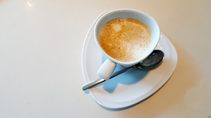 Top view of a white cup of coffee on white table