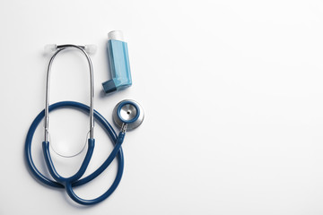 Asthma inhaler, stethoscope and space for text on white background, top view